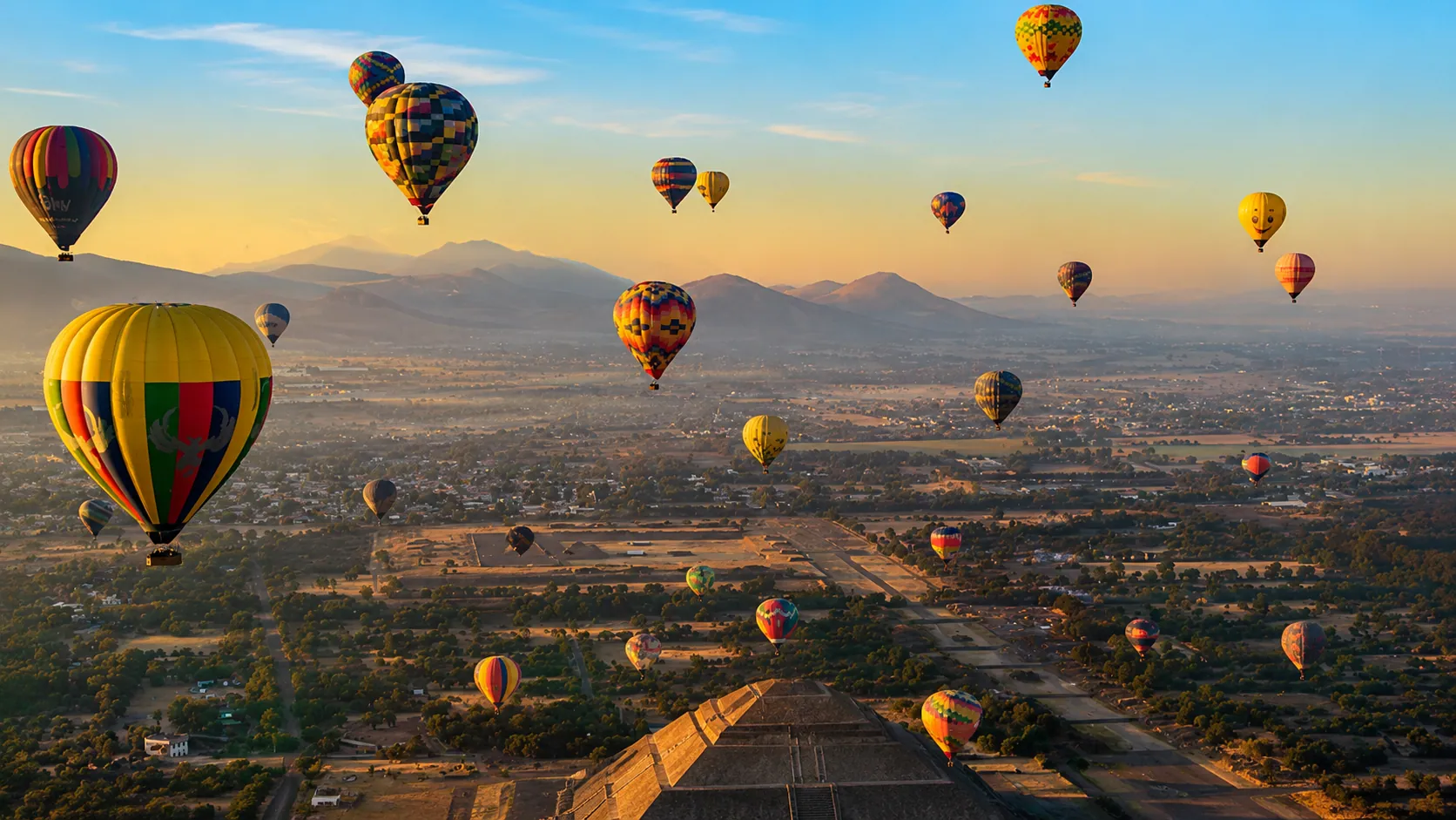 Dozens of hot air balloons over the Avenue of the Dead at Teotihuacán