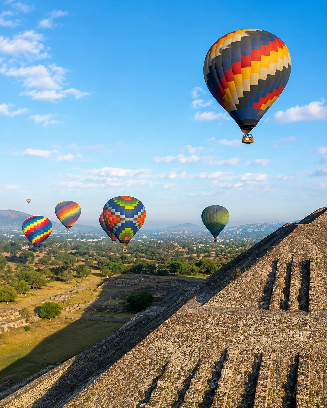 A hot air balloon flying beside the Pyramid of the Sun at sunrise